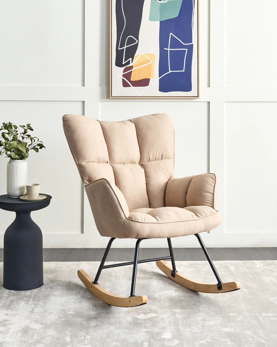 Beige rocking chair in a room with a side table and abstract art on the wall.