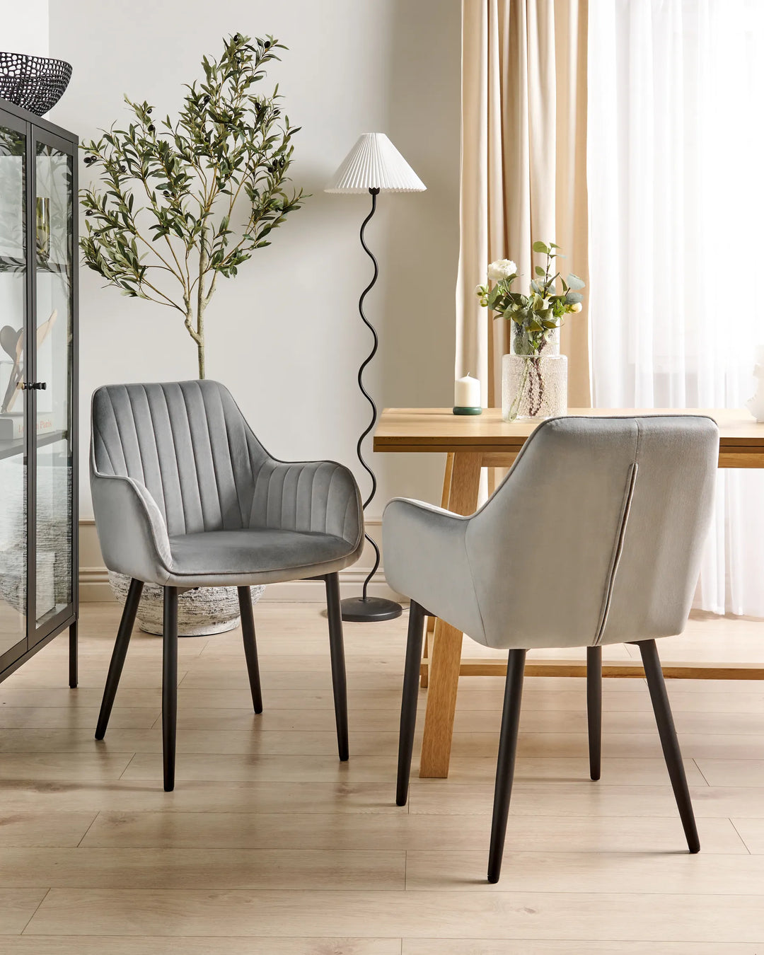 Modern dining room featuring grey velvet dining chairs paired with a wooden table, soft neutral tones, and stylish décor for a refined, inviting atmosphere.