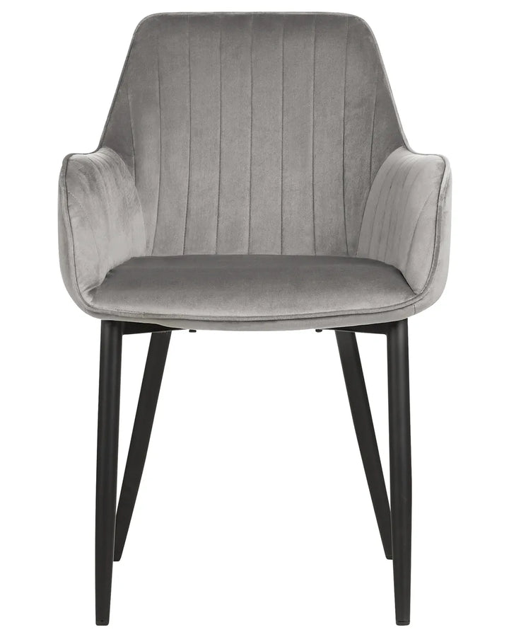 Grey velvet dining chair with integrated armrests, vertical channel stitching, and slim black metal legs, combining comfort with contemporary elegance.