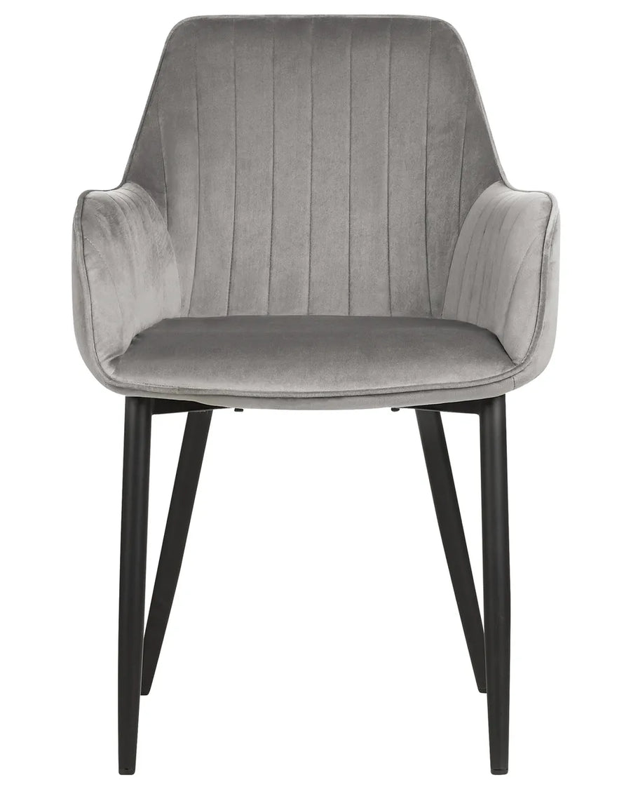 Grey velvet dining chair with integrated armrests, vertical channel stitching, and slim black metal legs, combining comfort with contemporary elegance.