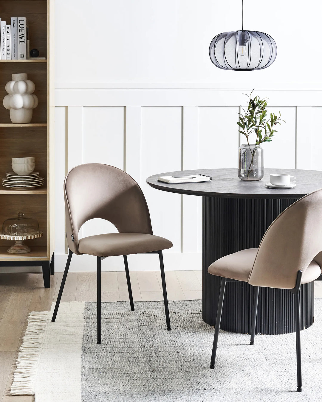 Stylish dining area featuring taupe velvet chairs paired with a black pedestal table, creating a sophisticated and contemporary atmosphere.