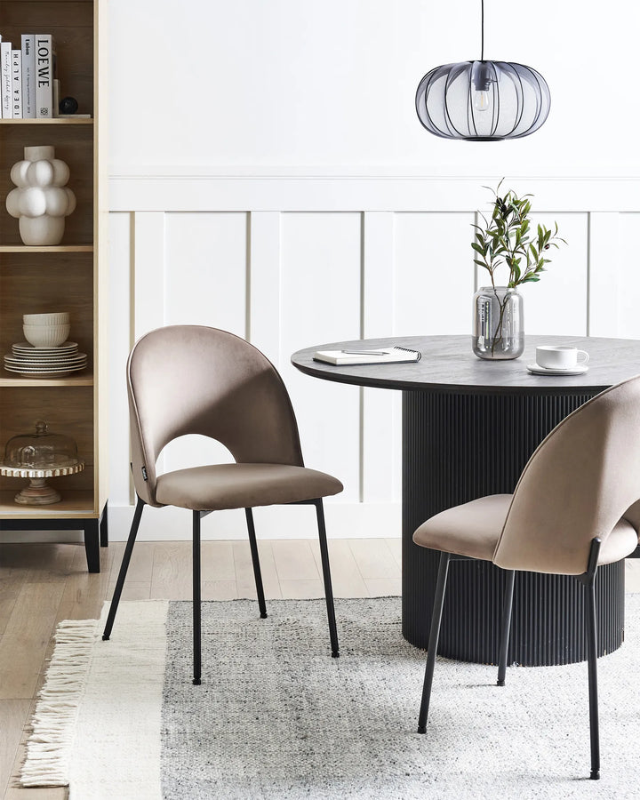 Stylish dining area featuring taupe velvet chairs paired with a black pedestal table, creating a sophisticated and contemporary atmosphere.