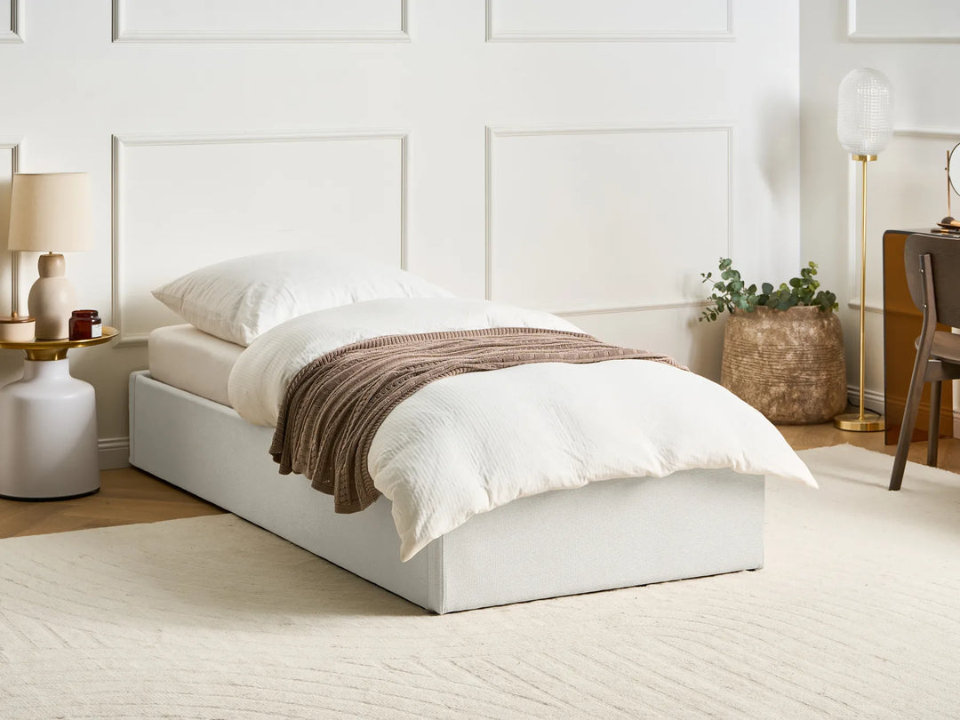 Bedroom with a white bed, brown blanket, and decorative items.