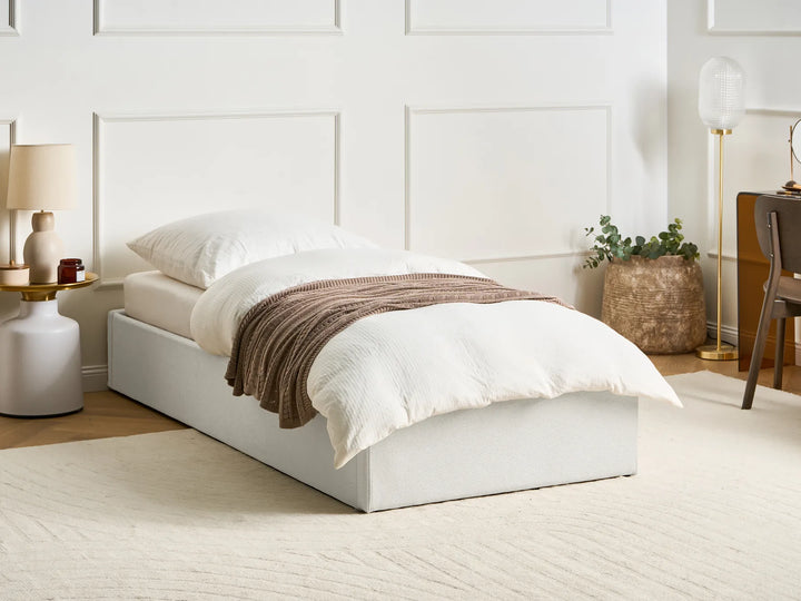 Bedroom with a white bed, brown blanket, and decorative items.