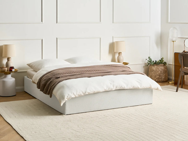 White bedroom with a neatly made bed, lamps, and decor.
