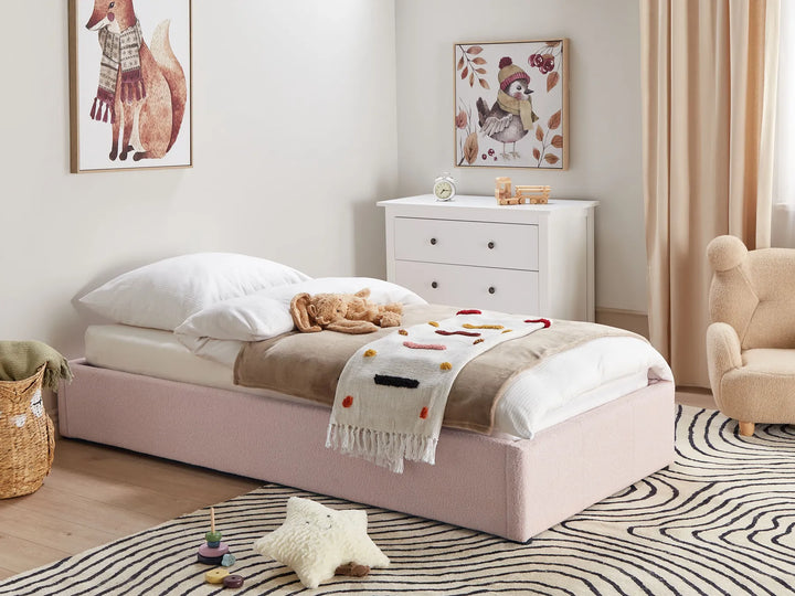 Children's bedroom with a pink bed, white dresser, and toys on a striped rug.