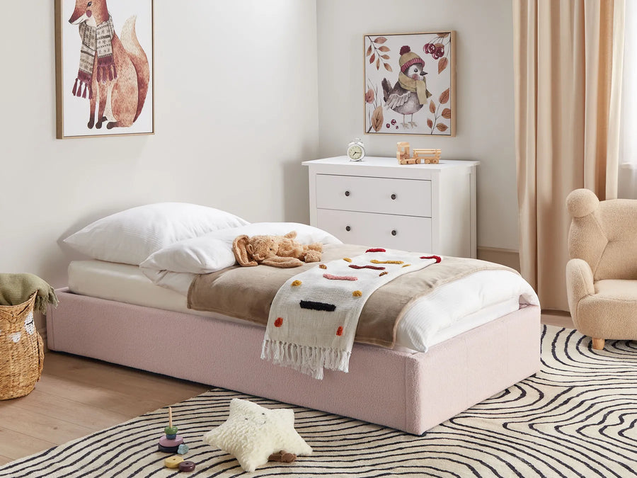Children's bedroom with a pink bed, white dresser, and toys on a striped rug.