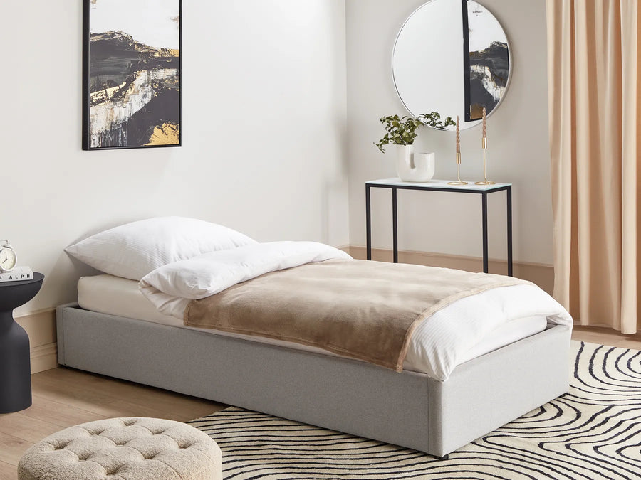 Modern bedroom with a bed, side table, mirror, and artwork.