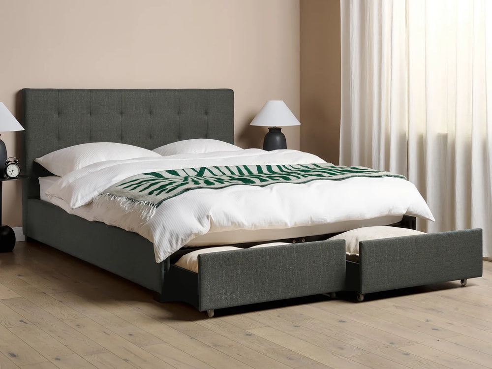 Gray upholstered bed with white bedding and a green blanket