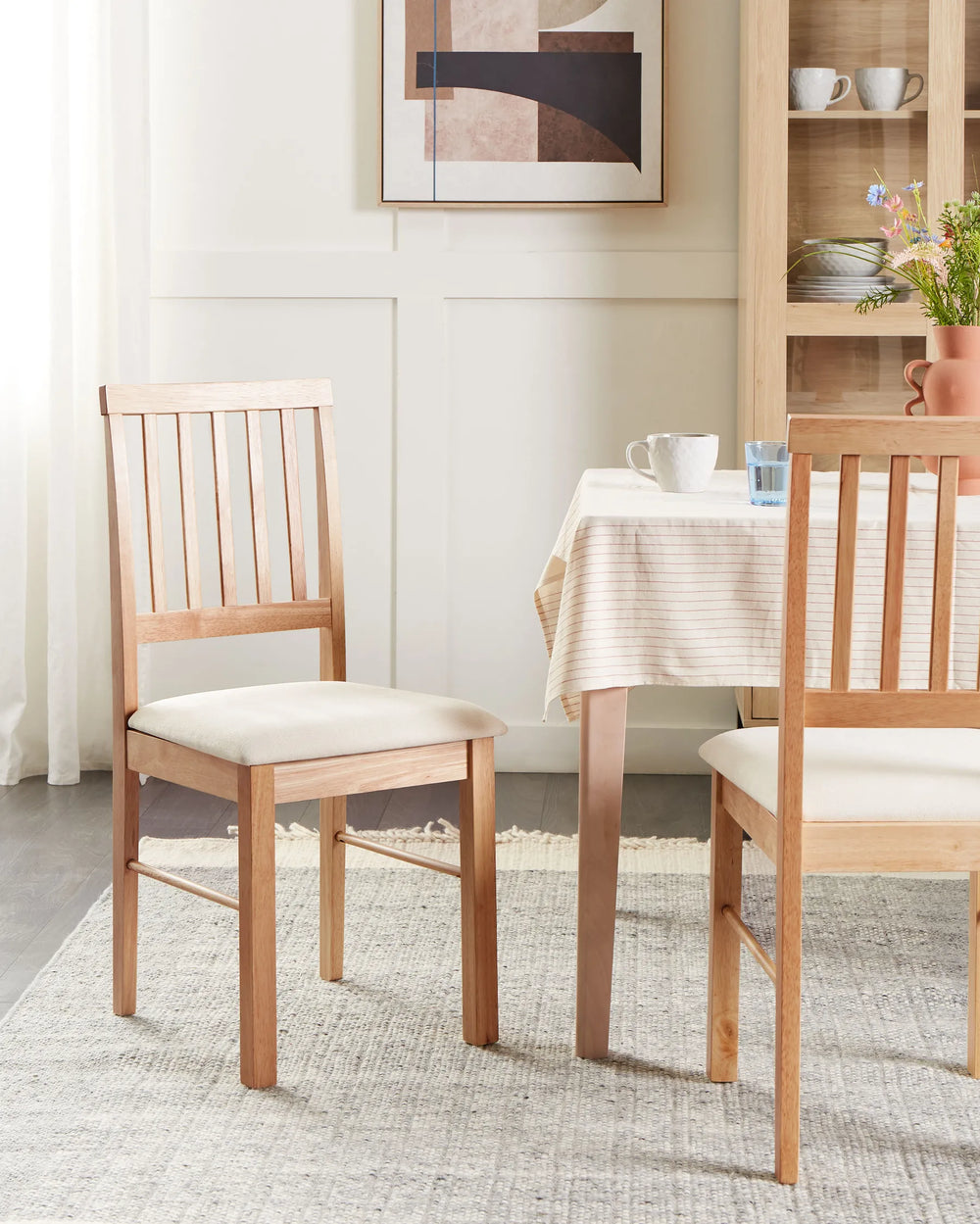 Wooden dining chairs styled in a bright, cozy dining setting with soft neutrals, warm oak finishes, and modern décor, creating a calm Scandinavian and contemporary farmhouse atmosphere.