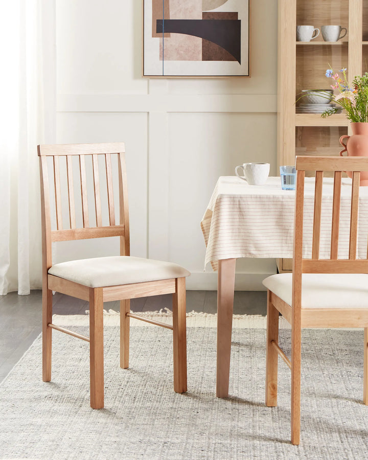Wooden dining chairs styled in a bright, cozy dining setting with soft neutrals, warm oak finishes, and modern décor, creating a calm Scandinavian and contemporary farmhouse atmosphere.