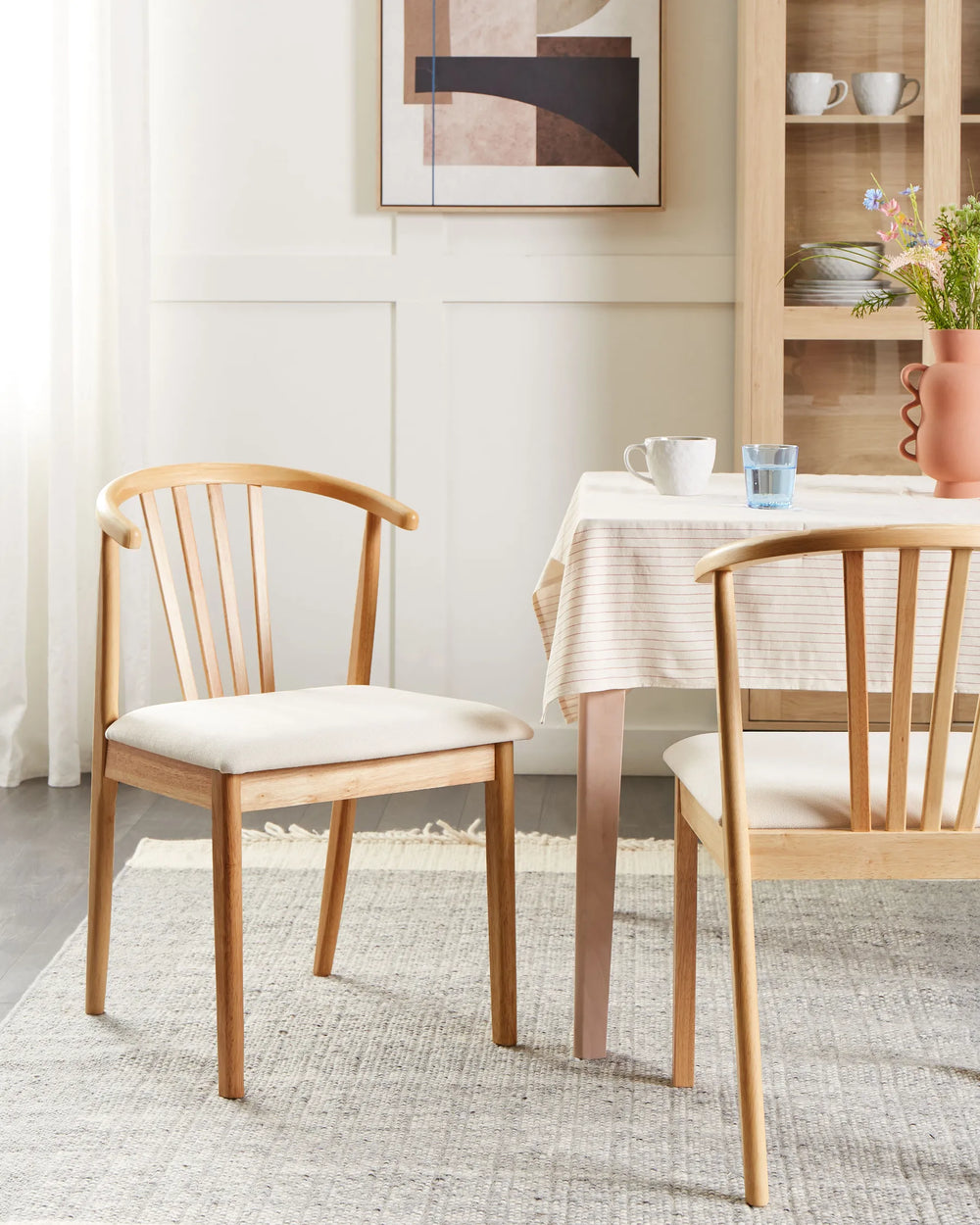 Light wood dining chairs with cream upholstered seats around a dining table in a bright dining room.
