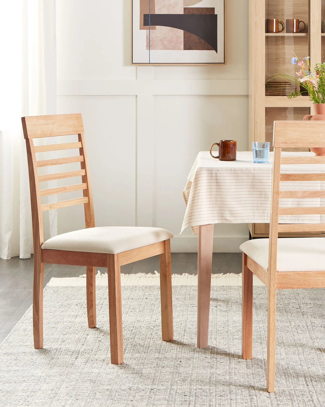 Styled in a bright and welcoming dining room, this wooden dining chair enhances the space with its warm natural tones and clean, understated silhouette. The cushioned seat adds everyday comfort, while the ladder-back detail introduces a subtle farmhouse-inspired touch, making it ideal for family dining areas, breakfast nooks, and casual entertaining spaces.