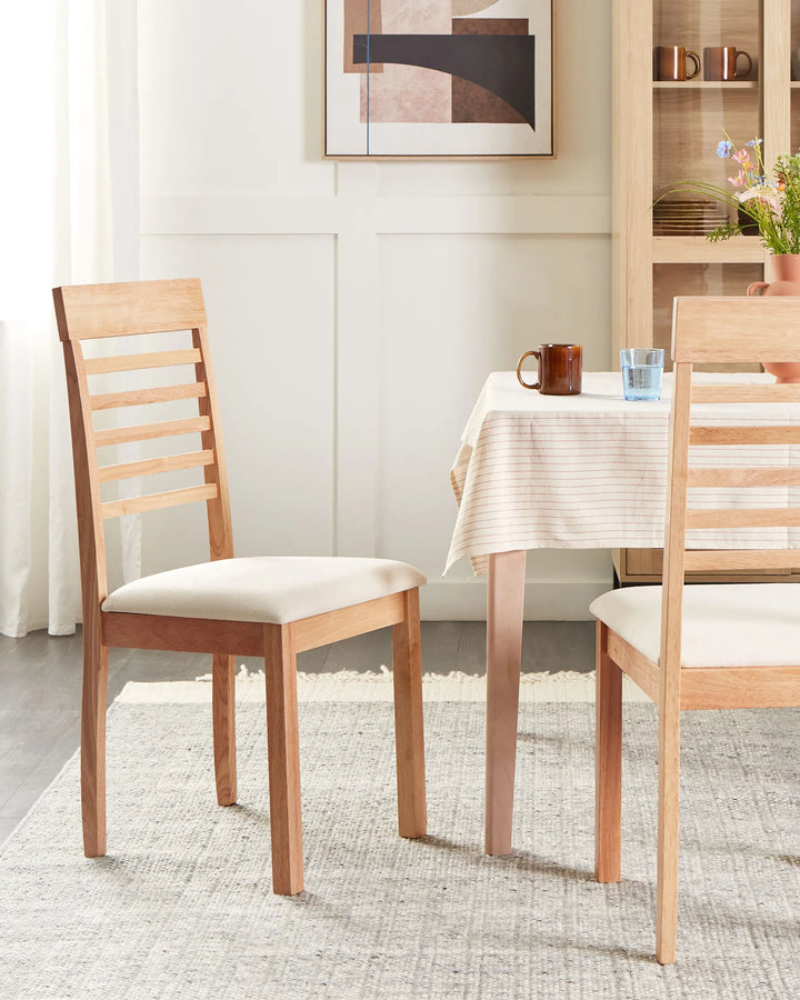Styled in a bright and welcoming dining room, this wooden dining chair enhances the space with its warm natural tones and clean, understated silhouette. The cushioned seat adds everyday comfort, while the ladder-back detail introduces a subtle farmhouse-inspired touch, making it ideal for family dining areas, breakfast nooks, and casual entertaining spaces.