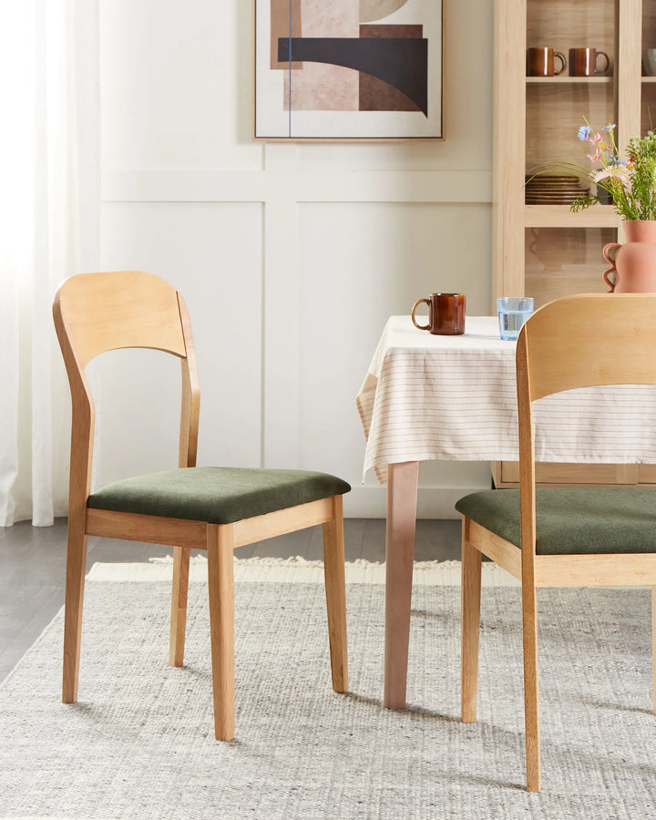Scandinavian-inspired dining chair styled in a warm neutral dining space, paired with a soft-textured rug, light wood furniture, abstract wall art, and muted green seating for a cozy modern aesthetic.