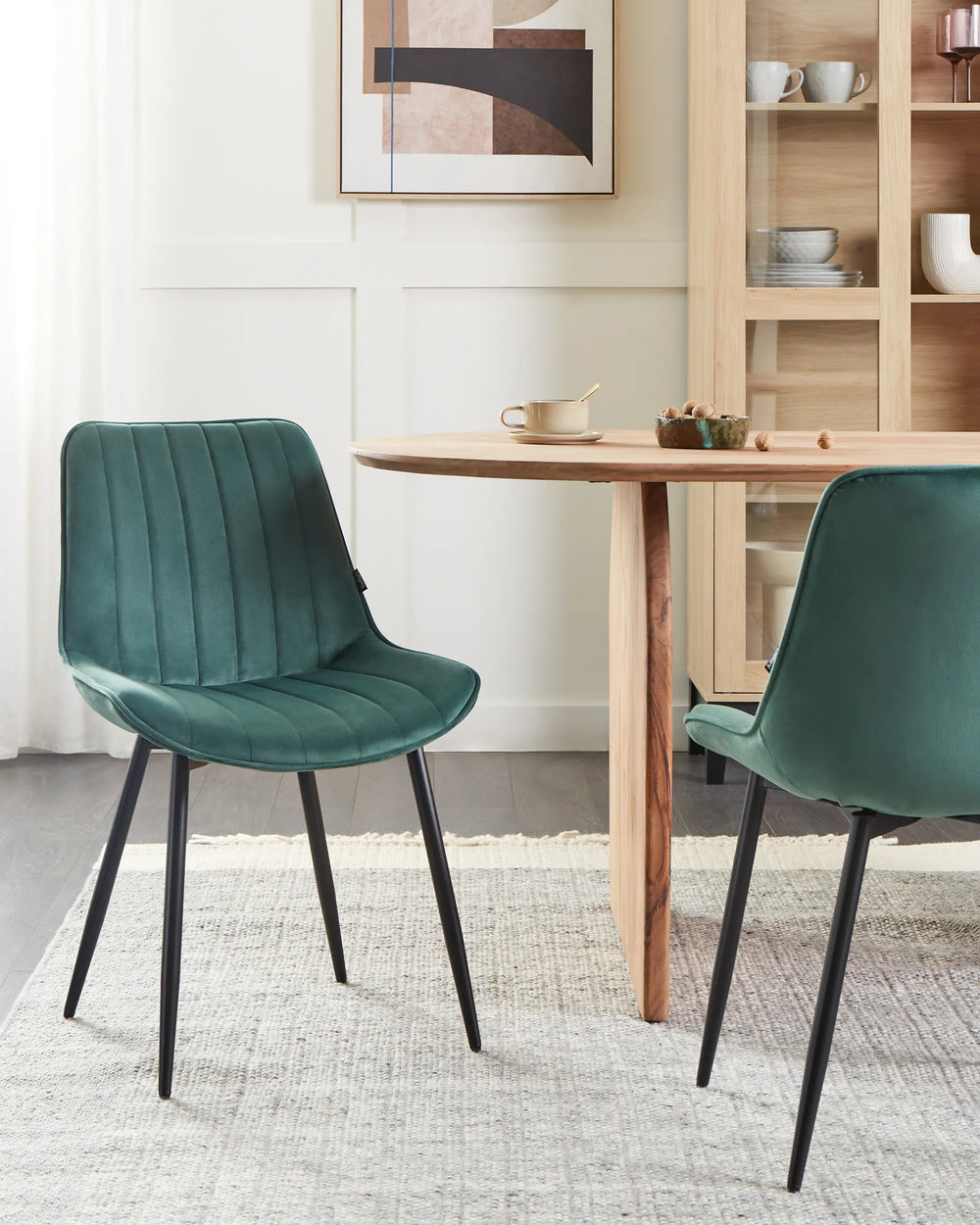 Contemporary dining area featuring rich green velvet chairs paired with natural wood elements, adding a sophisticated and inviting touch to the space.