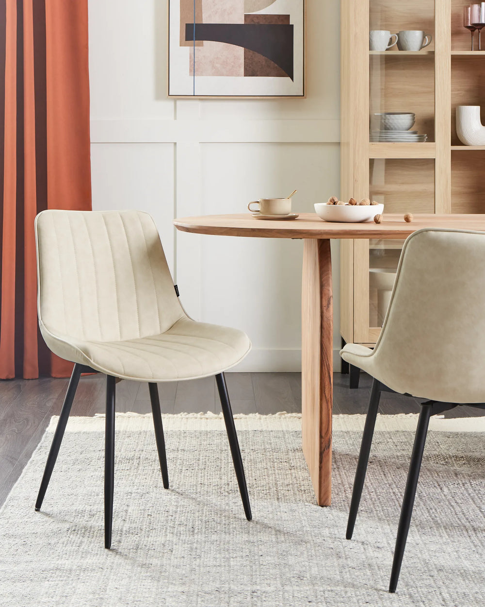 Elegant dining setup featuring the chair’s soft neutral upholstery, paired with natural wood furniture and warm accents to create a bright, contemporary atmosphere.