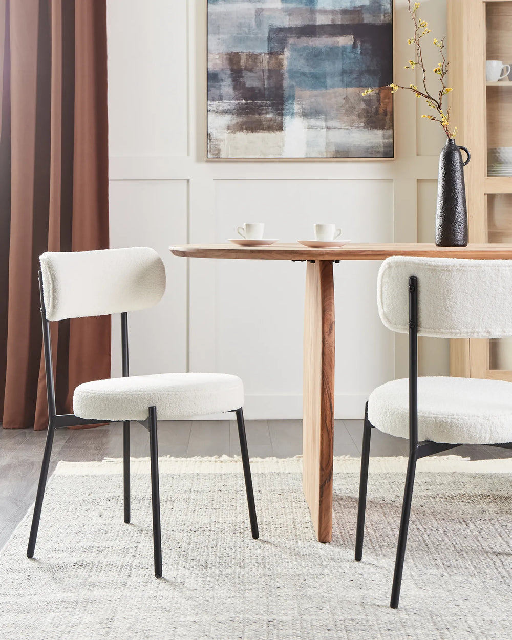 Off-white bouclé dining chairs paired with a natural wood table in a bright, modern dining space.