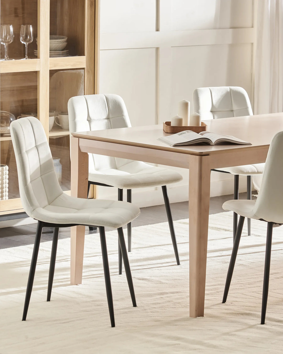 Bright dining space showcasing white upholstered chairs paired with natural wood furniture, creating a fresh, minimalist, and inviting atmosphere.