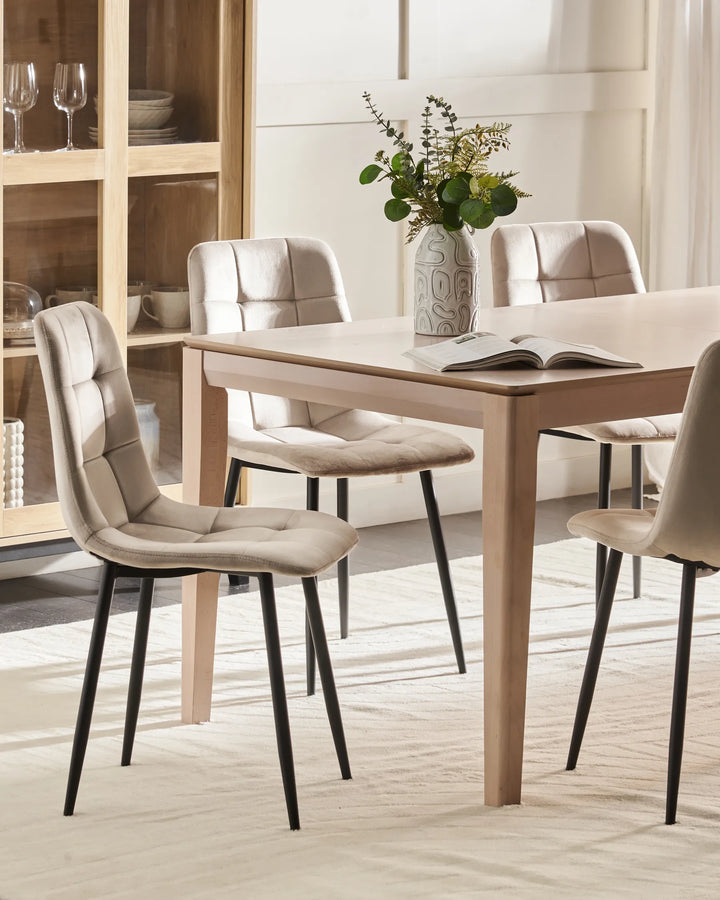 Light-filled dining room featuring beige velvet chairs around a natural wood table, creating a warm, sophisticated, and contemporary setting.