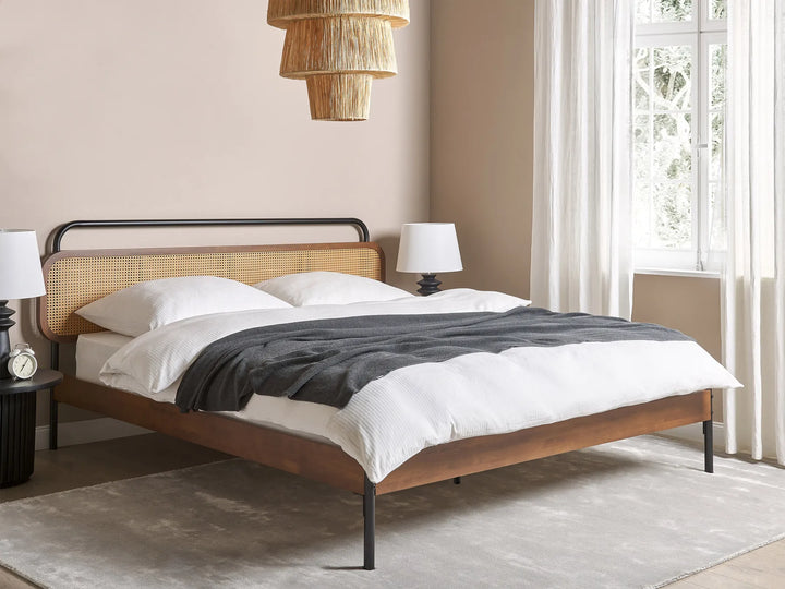 Wooden bed with white bedding and gray blanket in a bedroom setting.