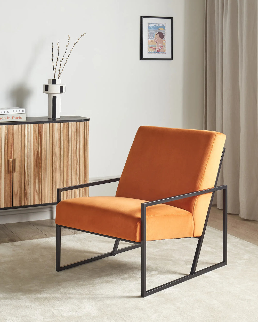 Orange armchair in a room with a wooden cabinet and framed picture on the wall.