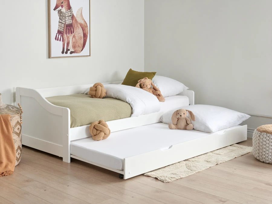 White children's bed with trundle and teddy bears in a room setting.