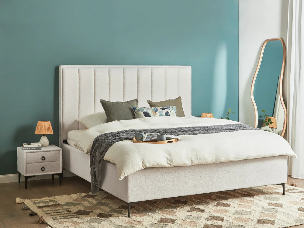 Neatly made bed with white bedding and decorative pillows in a bedroom setting.