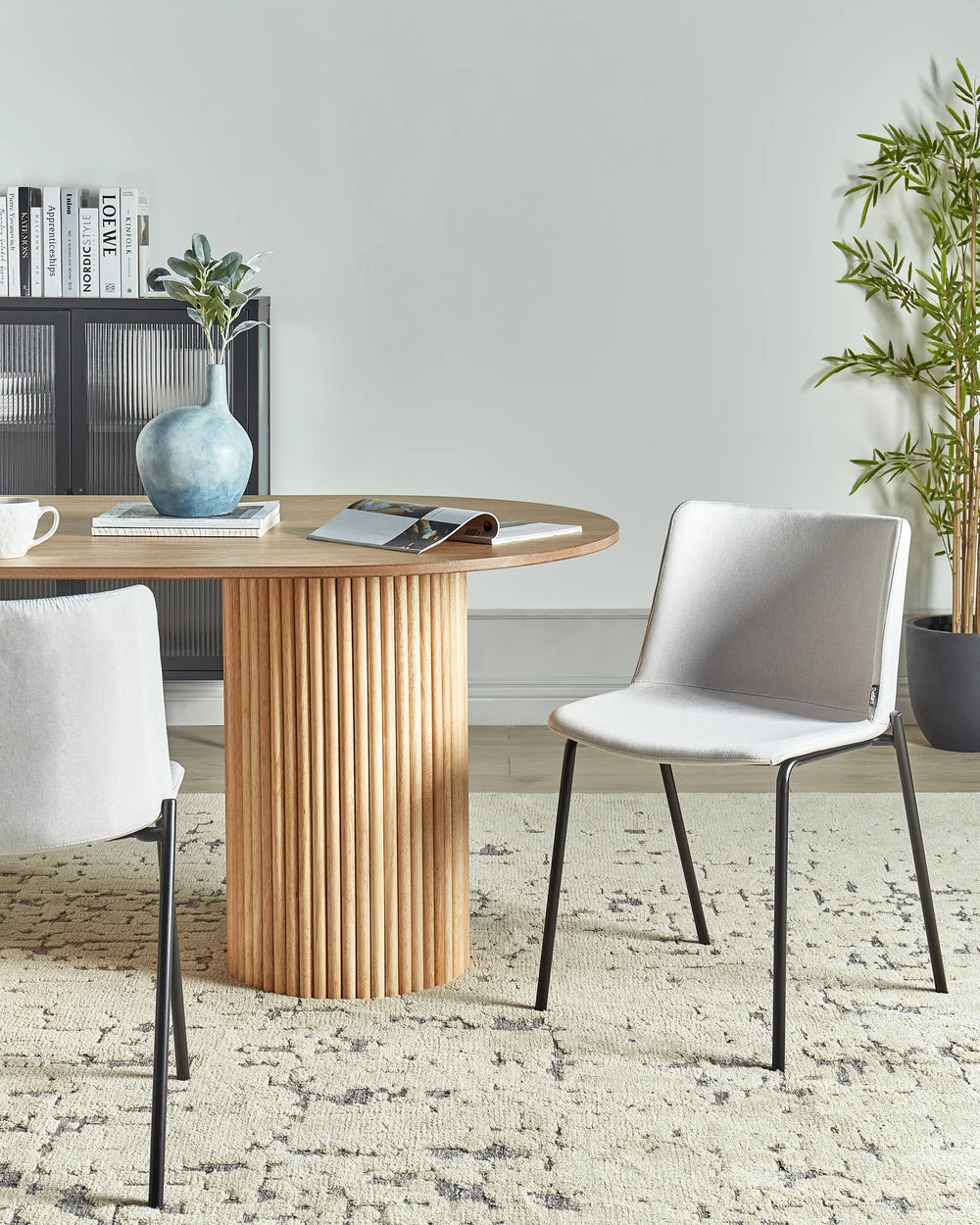 Light grey fabric dining chairs with black metal legs around a dining table in a contemporary dining space with modern décor.