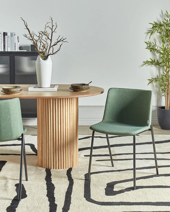 Dark green fabric dining chairs with black metal legs around a dining table in a contemporary dining space with modern décor.