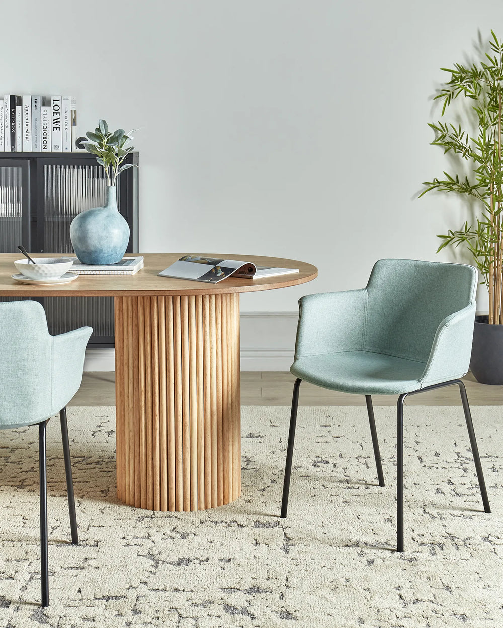 Mint green fabric dining chairs with integrated armrests and black metal legs around a dining table in a contemporary dining space with modern décor.