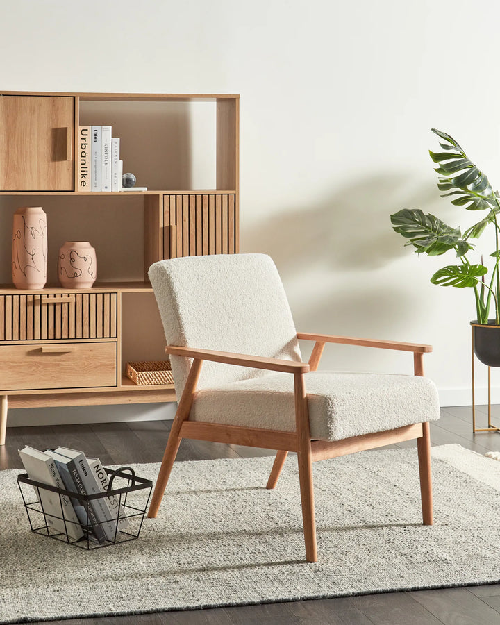 Wooden armchair with a light-colored cushion in a room with a wooden shelf and plant.