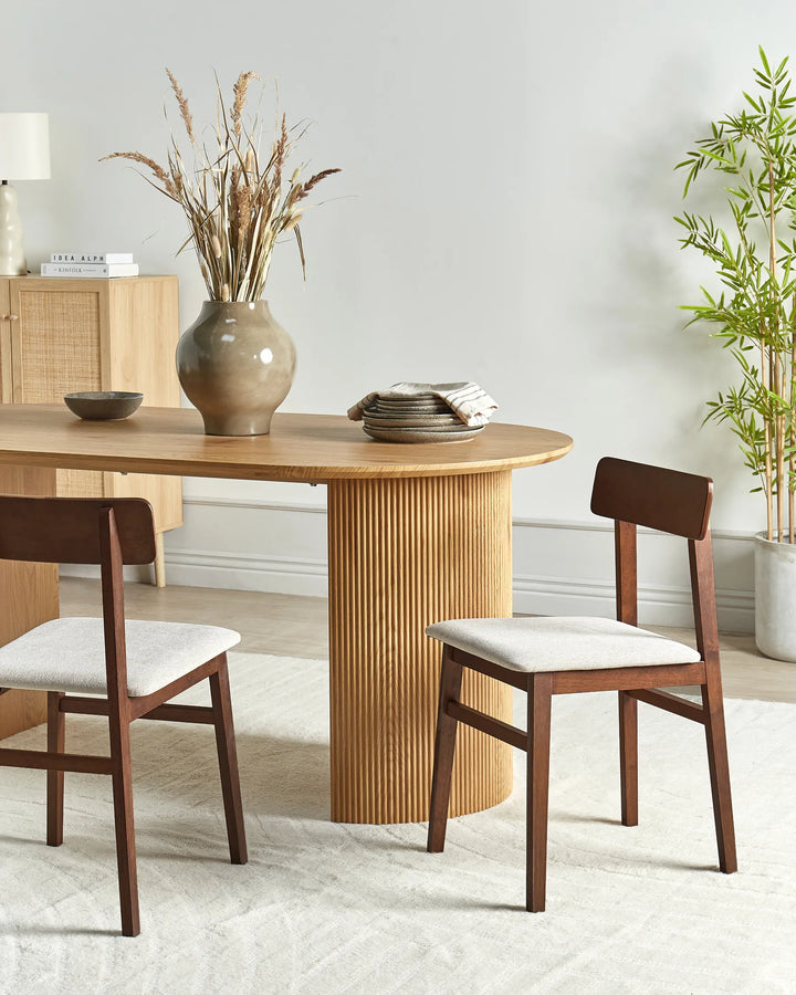 Set of dark wood dining chairs with light fabric seats around a modern wooden dining table in a bright dining room.