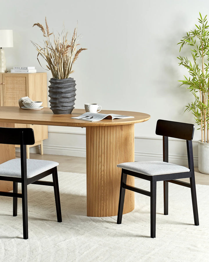 Black wooden dining chairs with grey upholstered seats around a wooden dining table in a modern dining room.