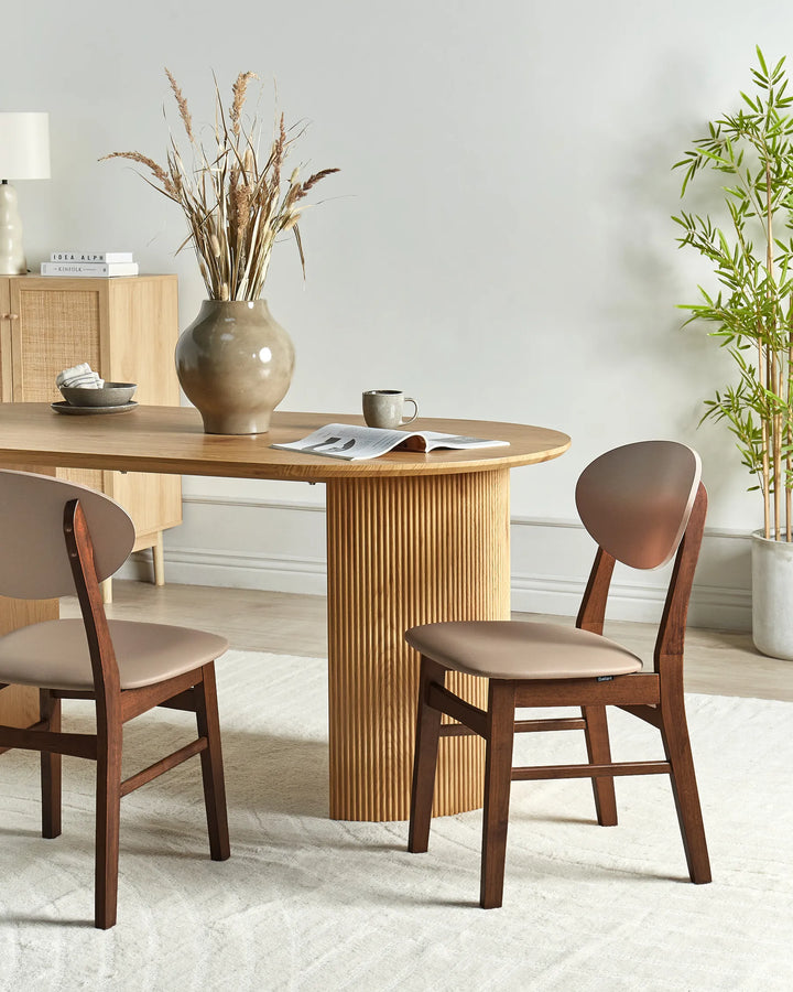 Walnut dining chairs with soft taupe upholstery styled around a round wooden dining table in a warm, modern interior with neutral décor, natural textures, soft lighting, and minimalist styling.