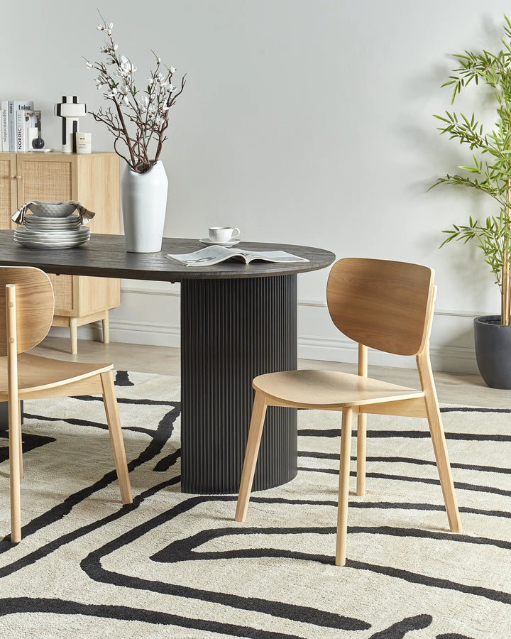 Modern Nordic-style dining chair styled in a bright contemporary dining space with a dark fluted pedestal table, soft neutral décor, organic textures, greenery, and a graphic rug for a clean, cozy, minimalist aesthetic.