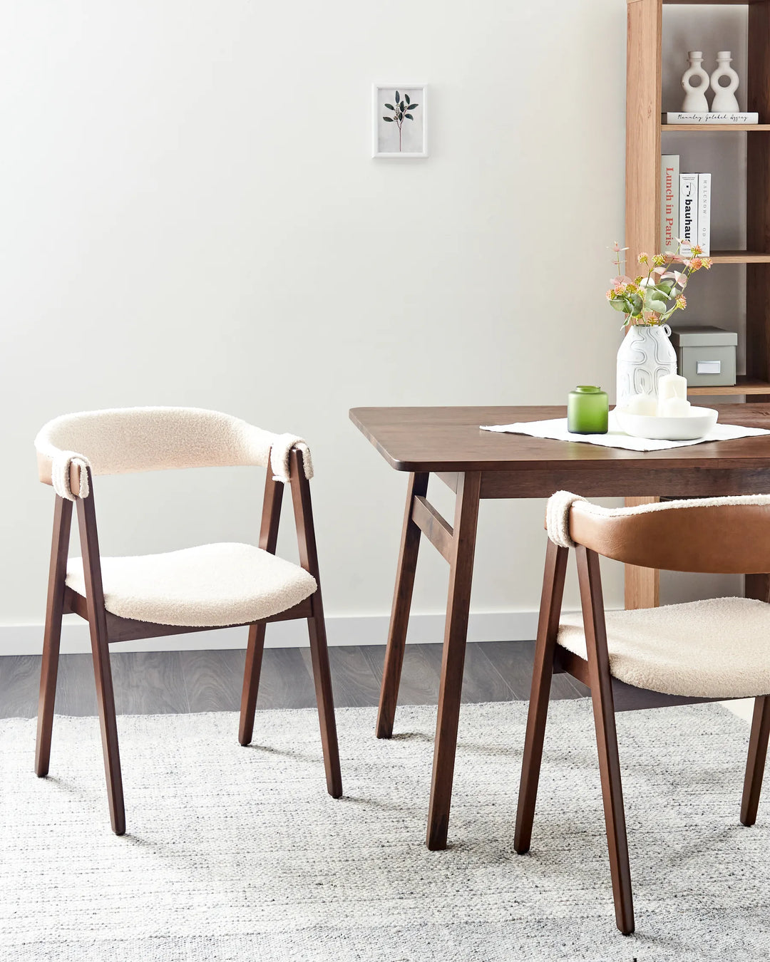 Cream bouclé chairs paired with a dark wood dining table, creating a cozy and sophisticated dining setting.
