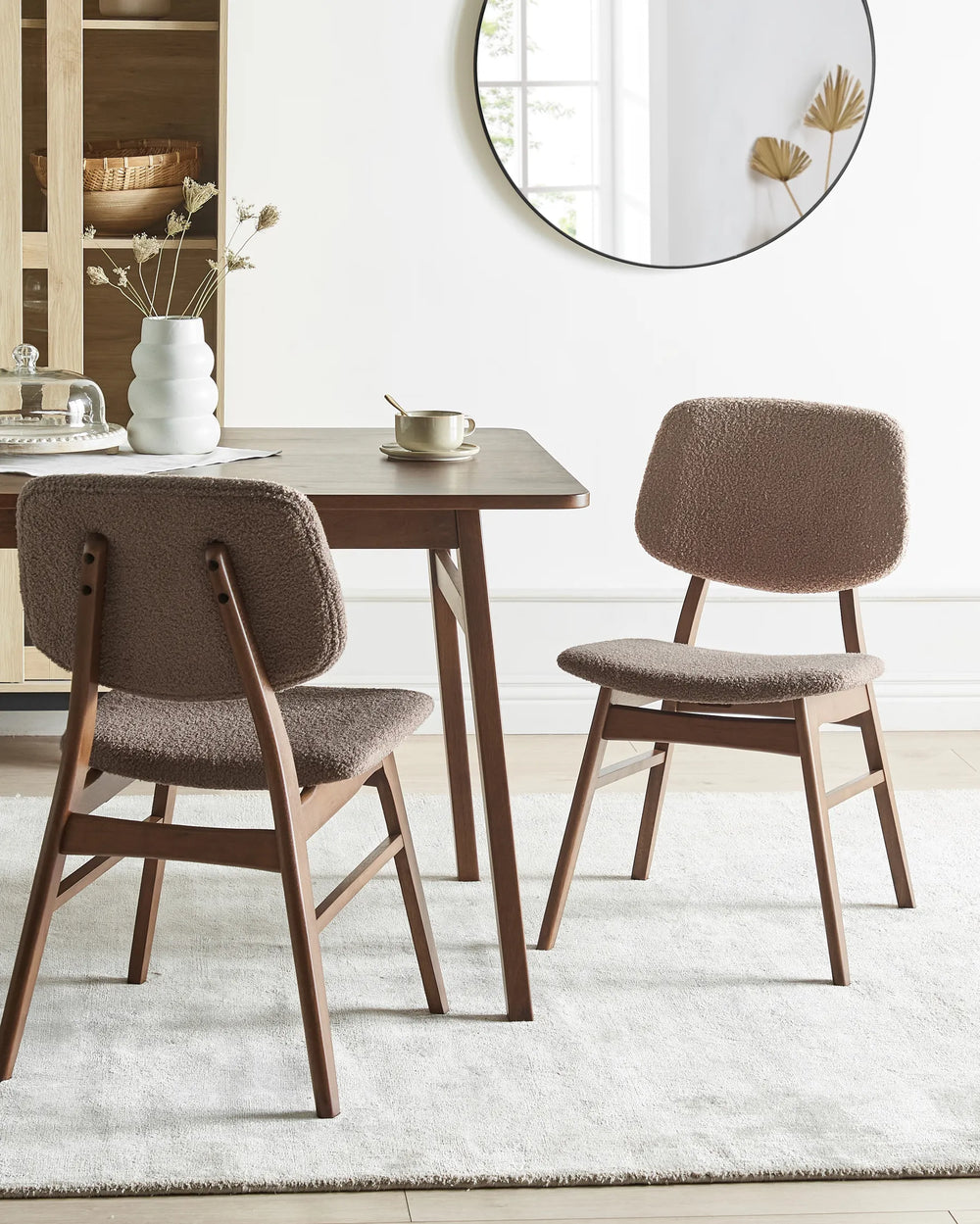 Elegant dining setting featuring textured brown bouclé chairs and rich wood furniture, creating a cozy, sophisticated atmosphere.