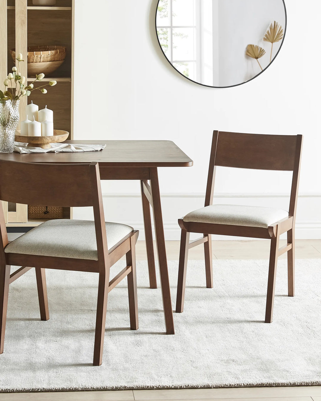 Dark wood dining chairs styled around a matching table create a warm, refined dining setting with neutral textures, minimalist décor, and a cozy contemporary atmosphere.