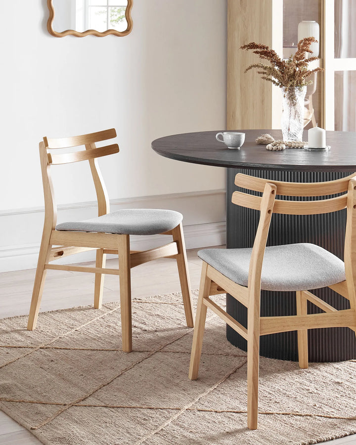 Styled around a modern dining table, these light wood dining chairs create a warm and welcoming atmosphere. The soft grey upholstery and natural wood finish complement neutral interiors, bringing effortless elegance and everyday comfort to the dining space.