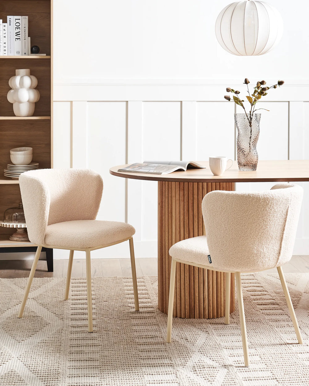 Soft, contemporary dining setting featuring bouclé chairs around a fluted wood table, creating a warm and inviting Scandinavian-inspired look.