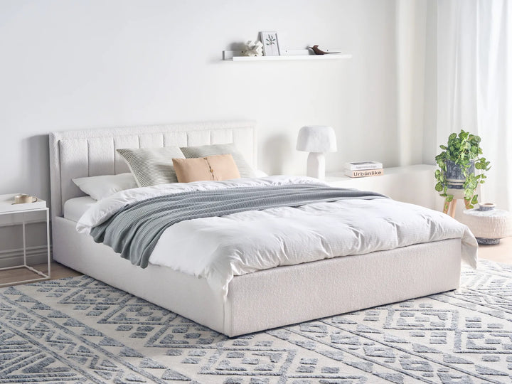 Neatly made bed with white bedding and gray blanket in a modern bedroom.