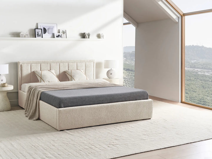 Beige upholstered bed in a modern bedroom with large windows.