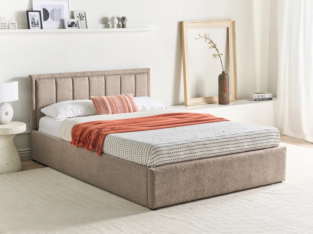 Beige upholstered bed with white bedding and orange throw blanket in a bedroom setting.