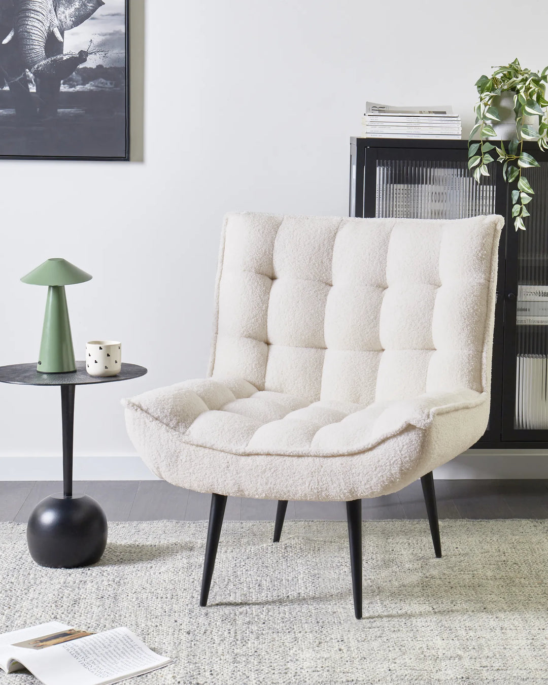 White upholstered chair in a living room setting with a side table and decor items.