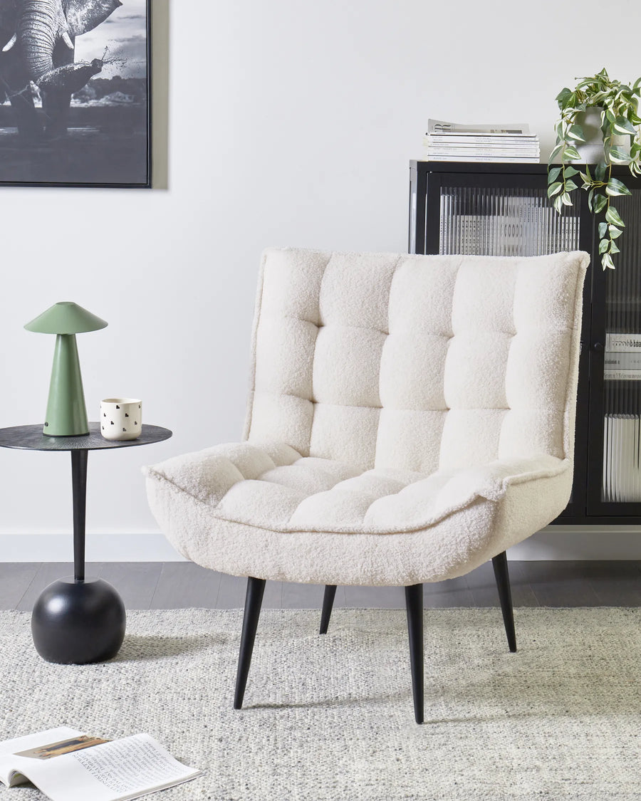 White upholstered chair in a living room setting with a side table and decor items.