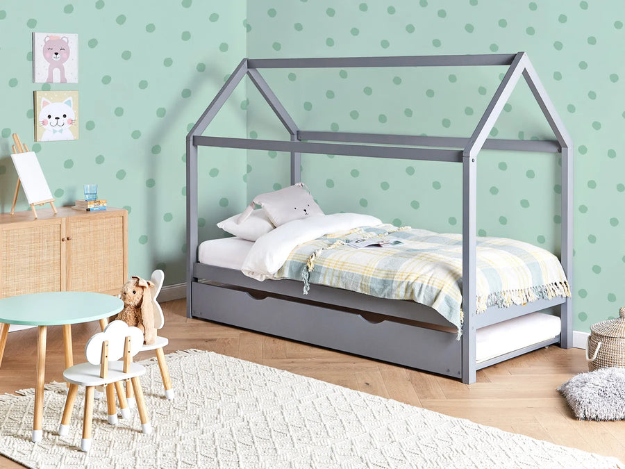 Children's room with a gray house-shaped bed, toys, and a polka dot wall.