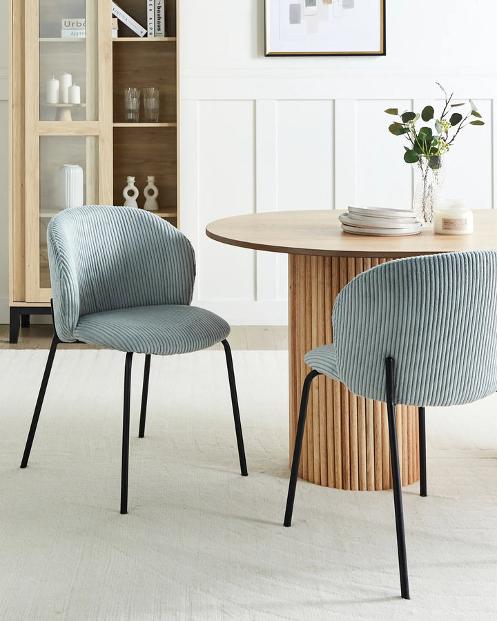Light blue corduroy dining chairs styled around a modern wood dining table in a bright contemporary interior.