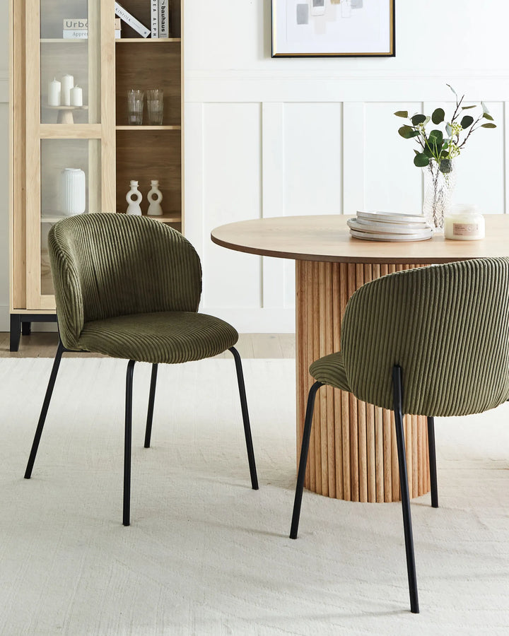 Olive green corduroy dining chairs styled around a modern wood dining table in a bright contemporary dining space.