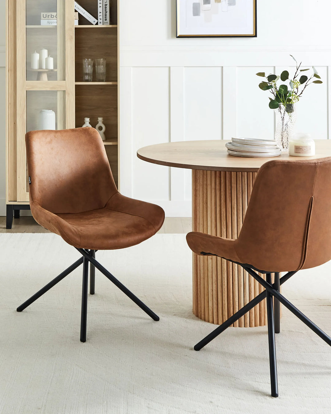 Brown dining chairs styled around a round wood table, adding warmth and contemporary character to a bright dining space.